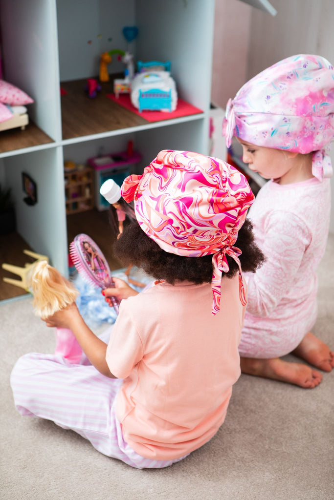 Two children playing together wearing Kidsilk hair wraps